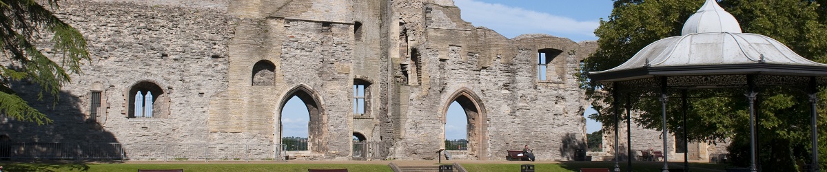 Newark Castle's long inner wall on a sunny day with the bandstand in the foreground